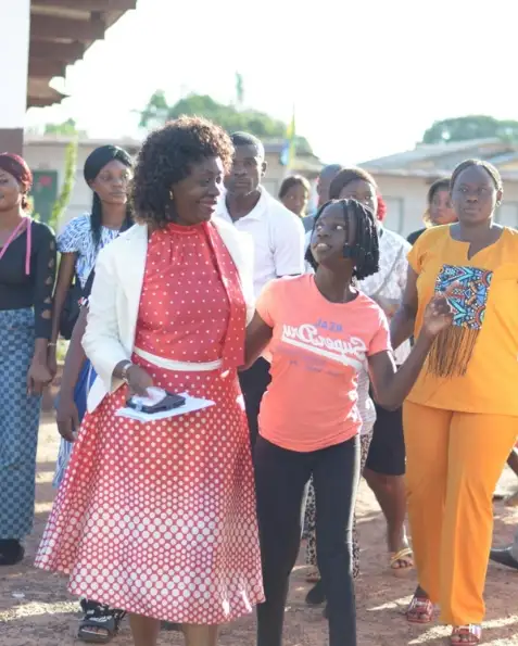 Honorine Mangomo caminando de la mano de una alumna en Franceville, rodeada de familias